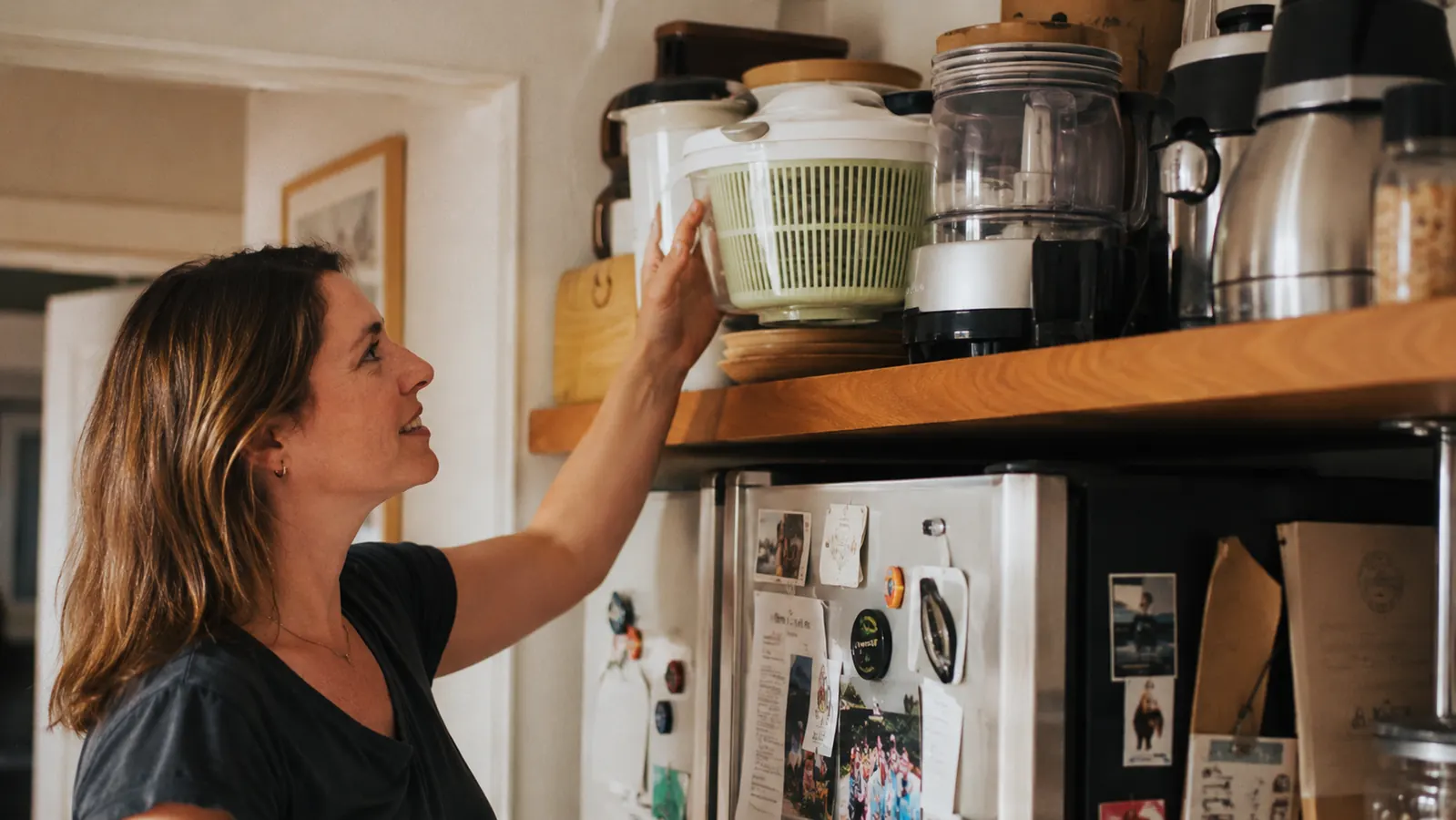 A small city kitchen shelf showing a salad spinner stored among a few frequently used cooking tools