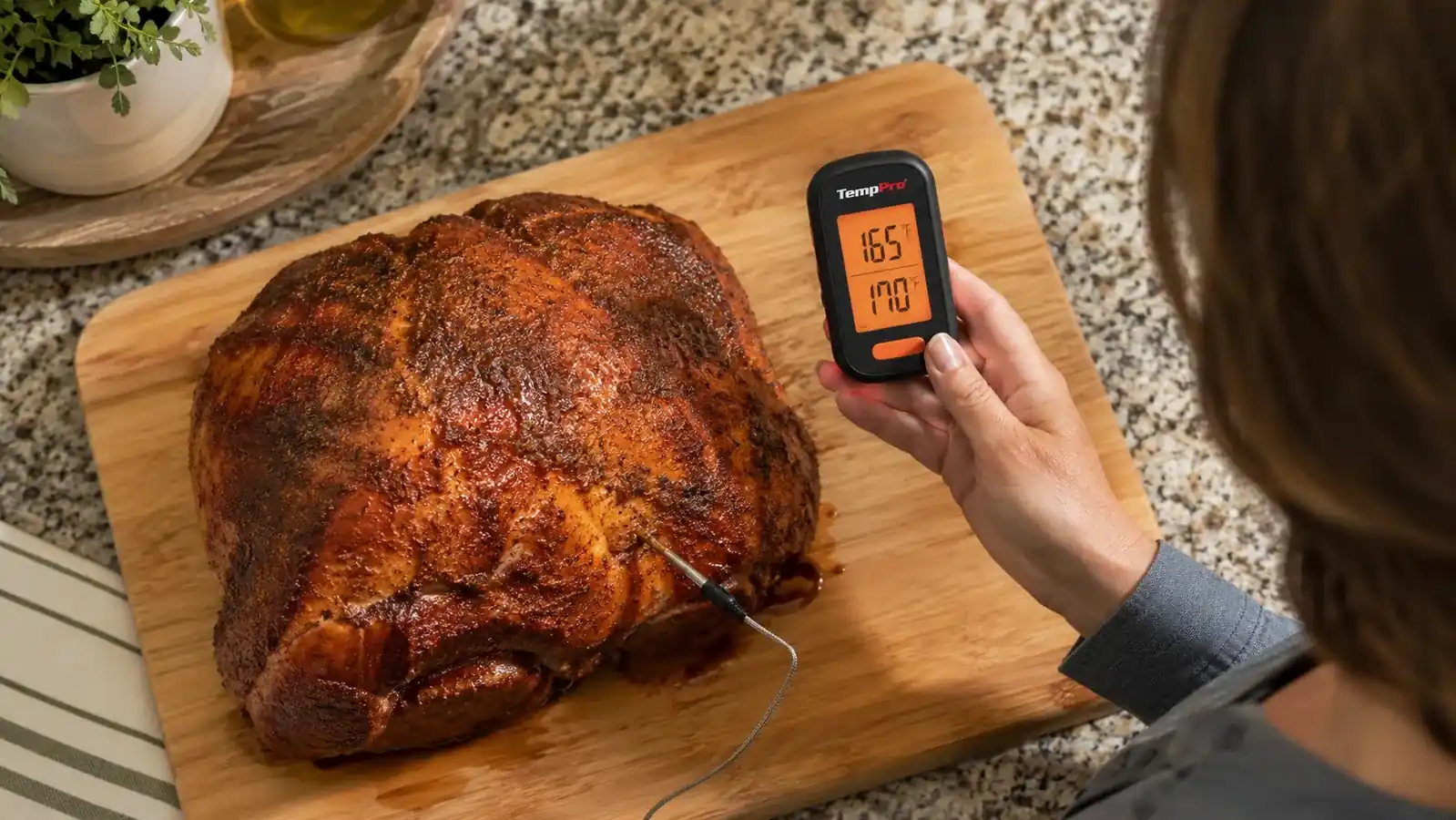 Close up of a dual probe thermometer's silver probe inserted into a pork shoulder next to an instant read reference thermometer checking the same spot