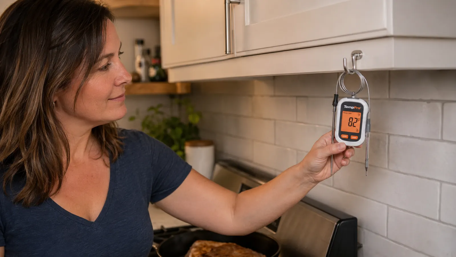 Digital thermometer hanging by its cord on a kitchen hook next to a cutting board, ready to grab